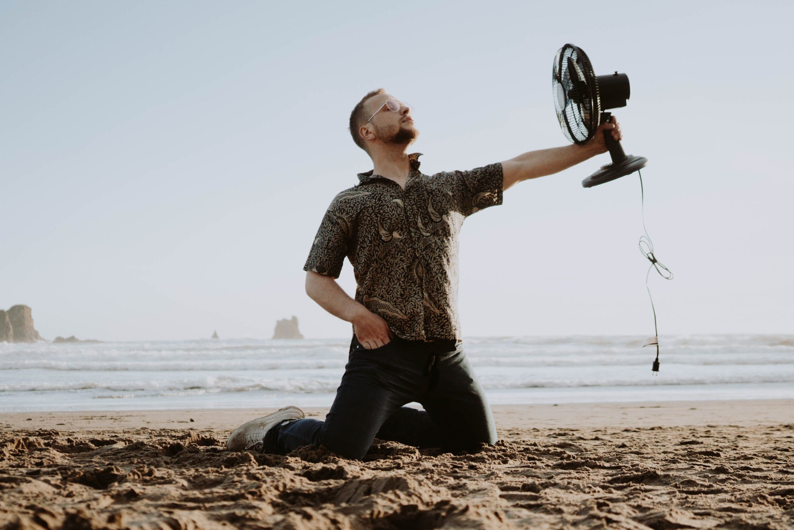 Man on knees holding fan on the beach